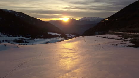 Drohne-Fliegt-über-Dem-Schnee-Durch-Das-Cortals-Tal-In-Andorra,-Das-Licht-Des-Sonnenuntergangs-Spiegelt-Sich-Im-Schnee,-Im-Hintergrund-Die-Pyrenäen
