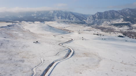 Luftaufnahmen,-Die-Sich-Vorwärts-Bewegen,-Zeigen-Einen-Schneebedeckten-Wander-,-Rad--Und-Laufweg,-Der-Zur-Hohen-Colorado-Bergkette-Führt,-Die-Mit-Eis-Gefroren-Und-Im-Winter-Mit-Nebligen-Wolken-Bedeckt-Ist