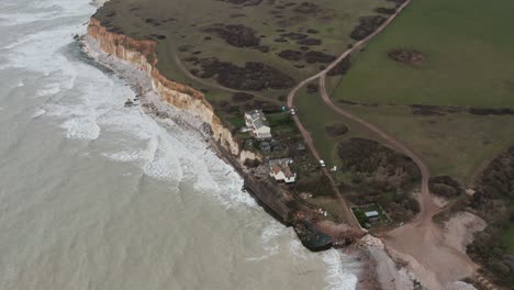 Rotating-drone-shot-of-small-cottages-on-white-chalk-cliffs-south-England