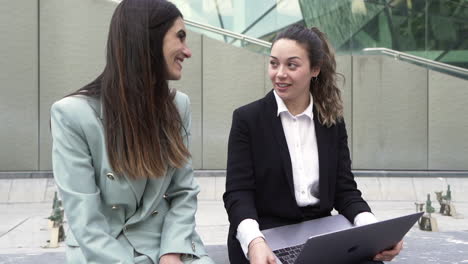Hand-held-shot-of-two-business-women-talking-and-laughing-at-laptop