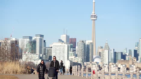 People-walking-in-Toronto-Canada,-enjoying-sunshine-with-CN-TOWER-in-background