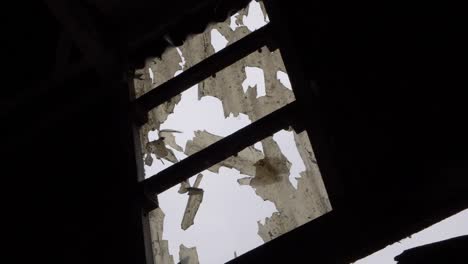 Broken-skylight-in-old-building-roof-medium-tilting-shot