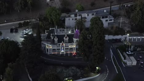 Exclusive-Magic-Castle-illuminated-at-night-in-Hollywood,-Los-Angeles,-aerial