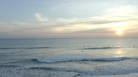 Wunderschöner-Strand-Auf-Der-Insel-Faro,-Der-Zur-Goldenen-Stunde-In-Warmem-Licht-Badet,-Menschen,-Die-Am-Strand-Spazieren-Gehen-Und-Einige-Auf-Den-Wellen-Surfen