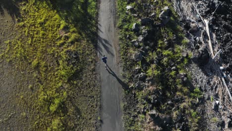 Man-running-on-path-early-in-the-morning-casting-long-shadow,-Aerial-View