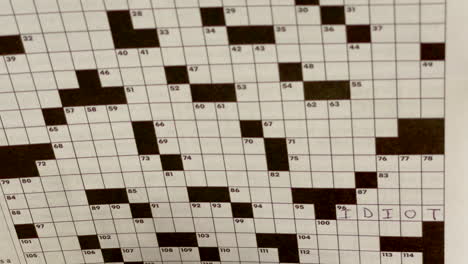Closeup-of-a-crossword-puzzle-with-only-one-answer-filled-in-with-black-pen,-idiot