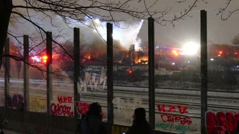 People-looking-at-a-big-fire-with-many-firefighter-trucks-at-the-scene