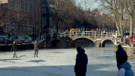 People-ice-skating-on-the-famous-Rapenburg-canal-in-Leiden,-the-Netherlands-during-the-pandemic