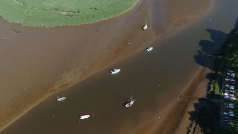 Aerial-of-the-river-exe-when-the-tide-is-out,-stranded-boats-and-resting-birds-scatter-the-shore