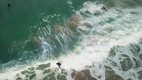 Fistral-Beach-in-Newquay,-England---Surfers-Having-Fun-At-The-Blue-Calm-Ocean---Drone-Shot