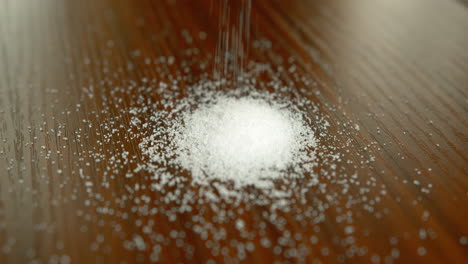 Close-Up-Slow-Motion-of-Granulated-Sugar-Being-Poured-onto-a-Table