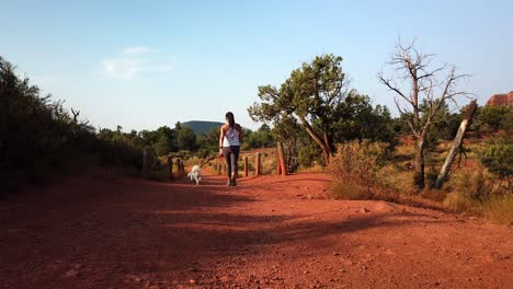 Woman-walking-pet-Maltese-dog-on-Sedona-desert-trail-path