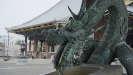 Dragon-Hand-Washing-Station-Chozuya,-Focus-Pull-Reveals-Higashi-Honganji-Temple