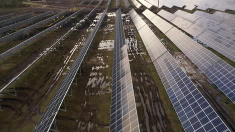 flying-over-in-construction-solar-power-plant,-there-are-muddy-tracks-between-solar-panels