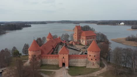 AERIAL:-Trakai-Island-Castle-on-a-Dull-and-Cloudy-Spring-Day-with-Lake-Surface-Rippling-from-Strong-Wind
