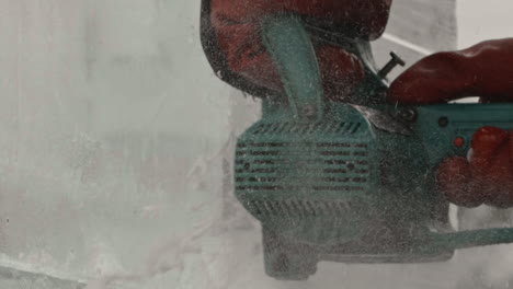 Extreme-close-up-of-electric-chainsaw-cutting-ice-block,-Slow-Motion