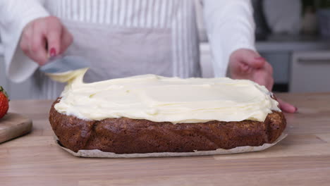 Bäckerin-Verteilt-Weißen-Zuckerguss-Mit-Spachtel-Auf-Karottenkuchen