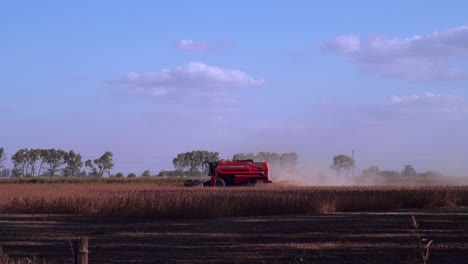 A-combine-harvests-soybean-under-the-late-afternoon-sun-leaving-a-dust-cloud
