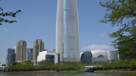 Lotte-Tower-and-other-skyscrapers-in-Seoul-downtown-Jamshil-area-daytime---view-from-near-the-Seokchon-lake,-wide-angle-static