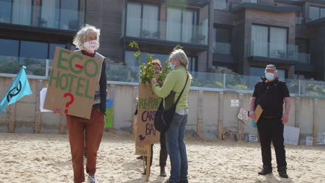 Frauen-Demonstrieren-Am-Strand-Vor-Dem-Carbis-Bay-Hotel-In-St.-Ives,-Cornwall,-Während-Ein-Mann-Zuschaut