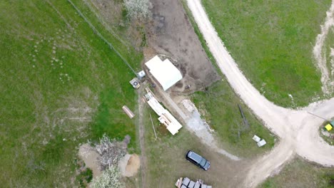 Top-view-from-a-drone-of-a-country-cottage,-road-and-pasture