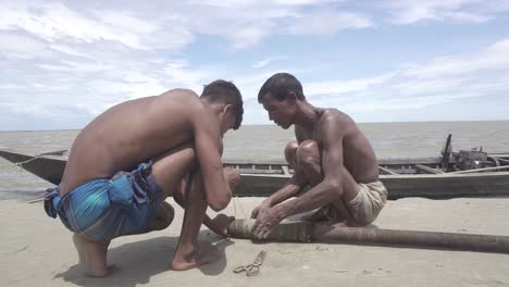 Two-fishermen-are-fixing-their-boat-on-the-bank-of-the-river