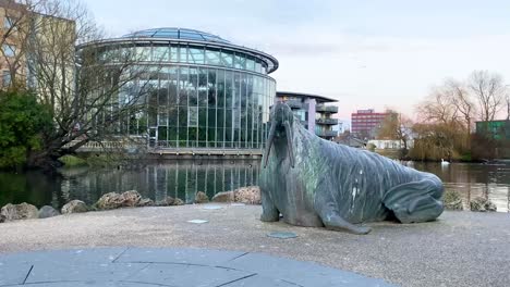 Large-Walrus-Statue-in-front-of-large-greenhouse-in-a-City-Park