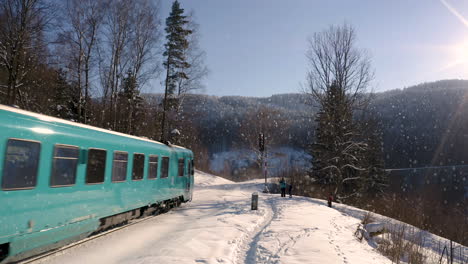 Familie-Wartet-Am-Bahnsignal-Im-Fallenden-Schnee-Darauf,-Dass-Ein-Zug-Vorbeifährt
