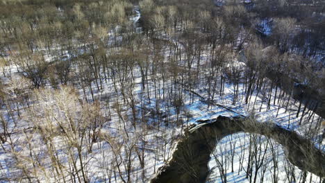 Drone-footage-above-winding-stream-in-winter-forest