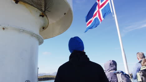 Waving-national-Iceland-flag-on-ship-while-people-admiring-view,-tilt-down-view