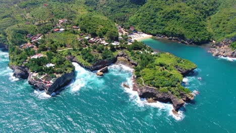 Coastal-village-in-lush-tropical-greenery-on-rocky-cliff-shoreline-aerial-view