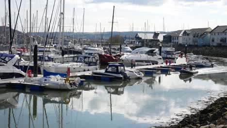 Racing-sports-team-dinghy-boat-cruising-through-sunny-Conwy-marina-luxury-yachts-waterfront-North-Wales