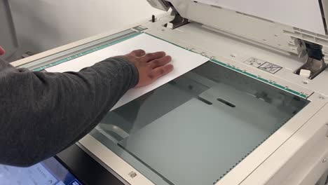 Man's-hand-adjusting-the-paper-or-document-on-a-copier-xerox-machine-to-make-a-copy