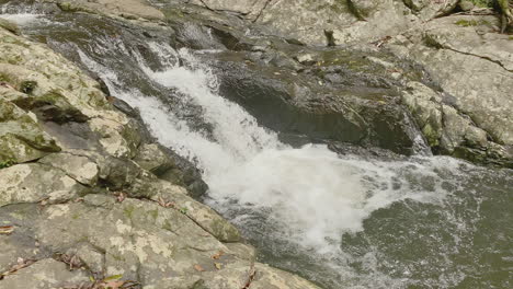 4K-UHD-of-fast-flowing-clear-freshwater-river-rapids,-cascading-over-a-prehistoric-bedrock-river-bed