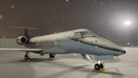 Snowflakes-falling-on-luxury-private-jet-plane-on-winter-airport-apron