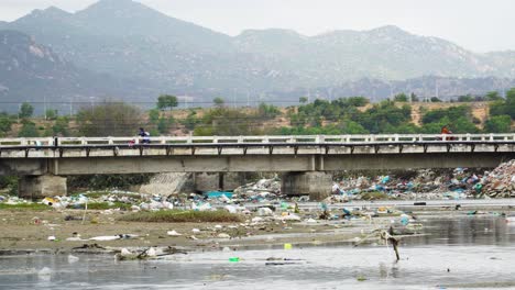 Bridge-over-river-extremely-polluted-by-plastic-rubbish-in-Son-Hai,-Vietnam