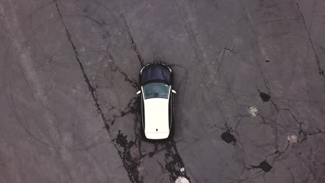 Aerial-top-view-above-a-black-and-white-Renault-Captur-car-parked-on-raw-asphalt