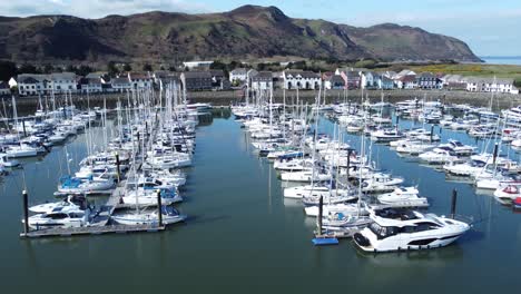 Luxury-yachts-and-sailboats-moored-in-Conwy-marina-mountain-waterfront-aerial-slow-dolly-left-view-North-Wales