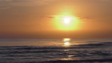 Hazy-sunrise-over-gentle-ocean-waves,-beach-view,-costa-blanca,-spain