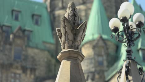 Beautiful-floral-design-concrete-pillars-at-the-gates-of-Parliament-Hill-with-the-Confederation-building-in-Ottawa,-Ontario,-Canada
