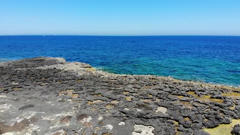 Aerial-view-of-Rocky-Limestone-Emerald-Blue-Beach-in-Sliema-Coastline,-Malta,-backwards-rising,-4K