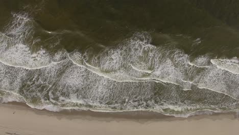 Slow-motion-aerial-view-of-low-tides-meeting-the-isolated-sandy-beach