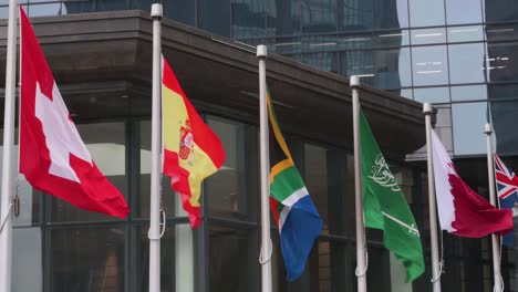 Nation-flags-of-Switzerland,-Spain,-South-Africa,-Saudi-Arabia,-Jordan,-and-New-Zealand-are-seen-waving-in-the-wind-in-Hong-Kong