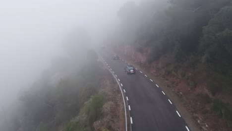 Vehículos-Que-Viajan-A-Través-De-La-Carretera-Nublada-Por-Las-Montañas-Del-Bosque-Durante-El-Día-De-Niebla-En-Barcelona,-España