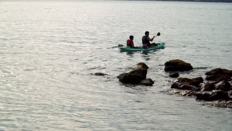 Two-skilled-men-enjoy-kayaking-in-the-sea-near-the-rocky-shore-of-Praia-da-Sepultura,-Brazil
