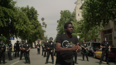 Afroamerikanischer-Mann-Klatscht-Stolz-Vor-30-Polizisten-Bei-Protesten-Tagsüber-In-Zeitlupe,-Aufgenommen-Mit-Roter-Kamera-4k