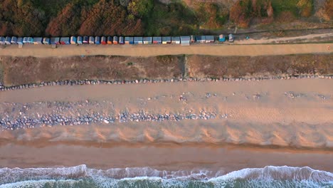 Top-down-tracking-drone-shot-of-Barton-on-Sea-sea-shore-at-sunset-in-Hampshire,-UK