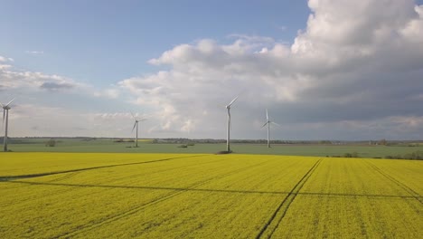 Yellow-canola-field-with-wind-mills-turbines-running-fast-4K