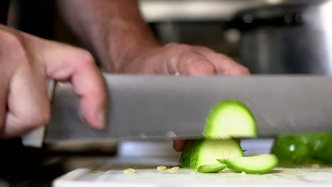 Close-shot-of-a-zucchini-being-chopped-on-a-white-table