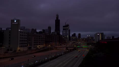 Cars-and-Subway-Pass-By-City-Skyline-Under-Dark-Clouds
